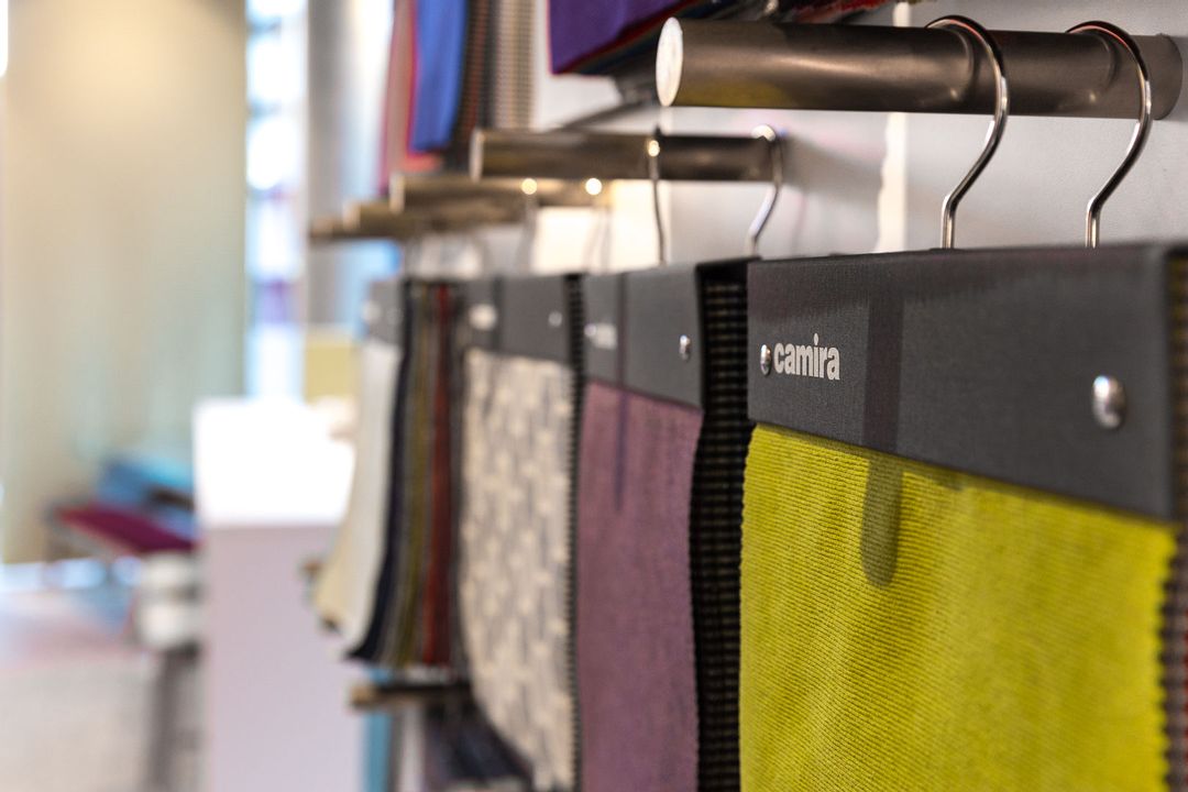 Close up of several of Camira's fabric swatches hanging from a bespoke made wall unit