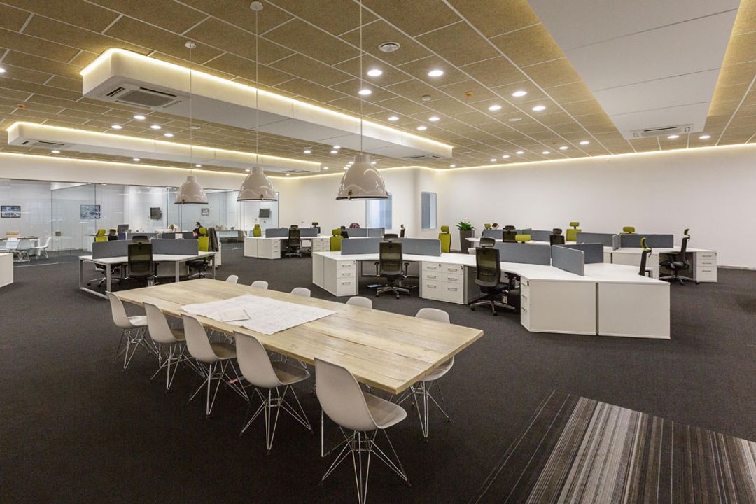 Main office area showing Vitra Eames side chairs surrounding a bespoke natural wood meeting table and banks of 180 degree workstations
