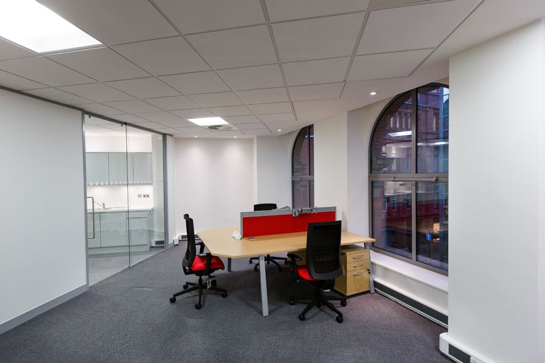 A bank of 3 desks with red desk mounted screen and red task seating.